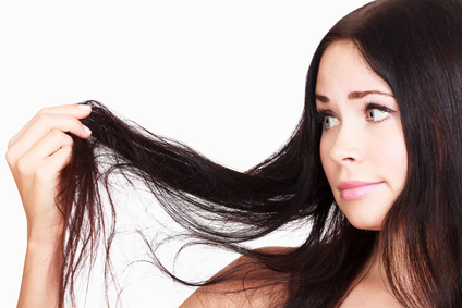brunette woman is not happy with her fragile hair, white background, copyspace